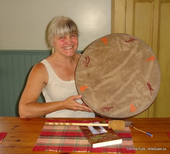 Noreen Kruzich holding a Native drum with totemic signatures of Algonkin and Nipissing chiefs.